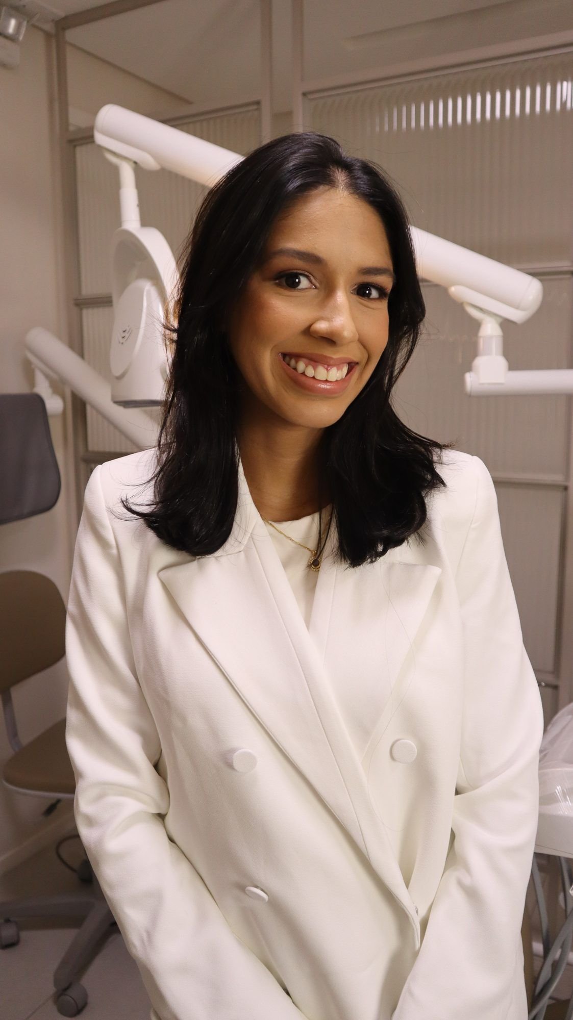 Dra. Débora sorrindo em seu consultório.